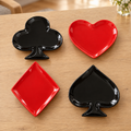 Noche de Cartas: cuatro platos de porcelana con formas de baraja en rojo y negro; ambientación ilustrativa creada con IA